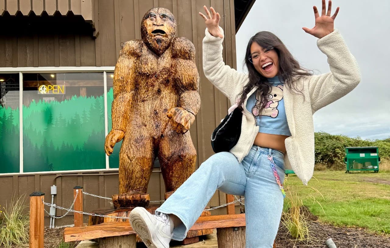 Sam posing excitedly with a carved Bigfoot statue